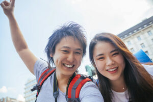 アジア人男女二人の旅行者が笑顔でセルフィーを撮っている
