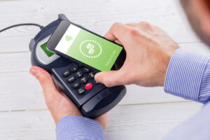 端末に黄緑色の画面のスマホをかざしモバイル決済している様子