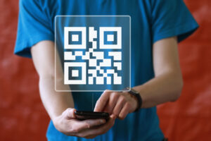 QRコードとスマホを持つ青いTシャツを着た男性