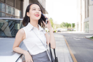 車に寄りかかりながら携帯電話で話す女性