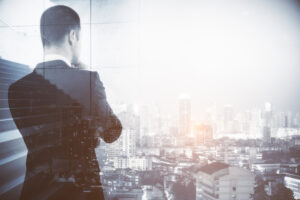 ビルから外の景色を眺めるビジネスマンの後ろ姿