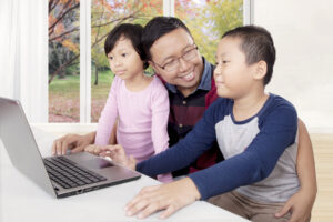 二人の子供とパソコンに向かう父親