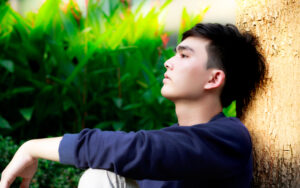 ナチュラルテイストなカジュアルファッションで遠くを物憂げに眺める黒髪のイケメン