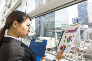 難しい顔で書類を眺めるスーツ姿の女性